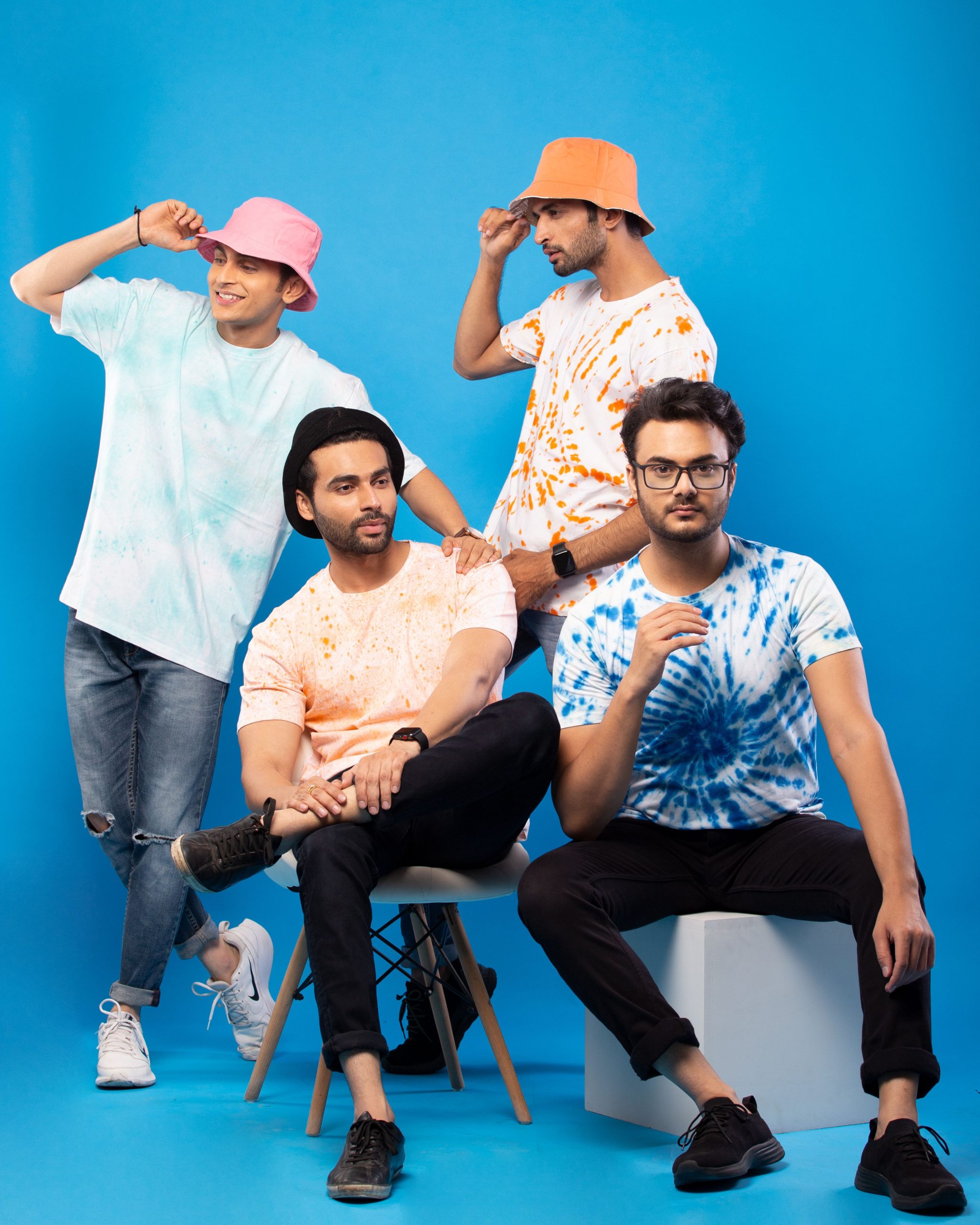 A stylish group of men posing in colorful tie-dye T-shirts in a studio setting.